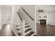 Interior staircase with wood treads and white risers leads to a living room with a fireplace at 304 Ashley Woods Ct, Clayton, NC 27527
