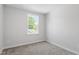 A simple bedroom with neutral walls and carpet, featuring a window providing a view of lush greenery at 308 White Oak Garden Way # 215, Garner, NC 27529