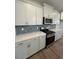 A bright kitchen with white cabinets, gray hexagon backsplash, stainless steel appliances, and wood floors at 308 White Oak Garden Way # 215, Garner, NC 27529