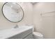 Neutrally decorated bathroom featuring a modern vanity, round mirror and white toilet at 3639 Nc Highway 39, Selma, NC 27576