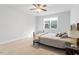 Large, carpeted bedroom with a ceiling fan and a wrought iron bed frame near window at 401 River Falls Dr, Apex, NC 27539