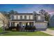 Charming two-story home features a covered front porch, manicured lawn, and attached two-car garage at 401 River Falls Dr, Apex, NC 27539