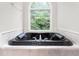Black soaking tub in a bathroom with marble accents, a large window, and serene natural views at 4639 Reid Rd, Elon, NC 27244