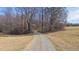 Long gravel driveway leading to a wooded property with open fields on either side under a clear sky at 4639 Reid Rd, Elon, NC 27244