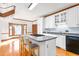 Sunlit kitchen boasts an island with seating, white cabinets, and hardwood floors, creating a warm, inviting space at 4639 Reid Rd, Elon, NC 27244