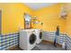 Bright laundry room featuring a side-by-side washer and dryer, cheerful yellow walls, and convenient shelving at 4639 Reid Rd, Elon, NC 27244