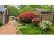 Landscaped backyard featuring a brick path, a shed, vibrant flowering plants, and a wooden fence at 610 Westbrook Dr, Burlington, NC 27215