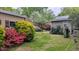 Spacious backyard with lush landscaping, including colorful flowering bushes, and a brick path at 610 Westbrook Dr, Burlington, NC 27215