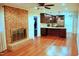 Open concept living room featuring a brick fireplace, hardwood floors, and an adjacent kitchen area at 610 Westbrook Dr, Burlington, NC 27215