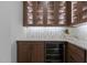 Elegant bar area featuring glass-front cabinets, mosaic backsplash, and a built-in wine cooler at 7621 Wingfoot Dr, Raleigh, NC 27615