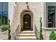 Inviting front entrance with an arched doorway, brick facade, manicured landscaping, and stone steps at 7621 Wingfoot Dr, Raleigh, NC 27615