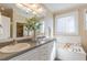 Bathroom featuring double sinks, a soaking tub with tile surround and an adjacent window at 10 Georgetown Woods Dr, Youngsville, NC 27596