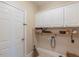 Practical laundry room with white cabinets, storage shelves, a broom and space for laundry appliances at 10 Georgetown Woods Dr, Youngsville, NC 27596