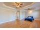 Bright main bedroom featuring hardwood floors, tray ceilings with ceiling fans, and a walk-in closet at 10 Georgetown Woods Dr, Youngsville, NC 27596