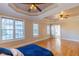 Large primary bedroom featuring hardwood floors, large windows, and tray ceilings at 10 Georgetown Woods Dr, Youngsville, NC 27596