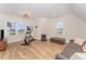Bright bonus room with wood floors, an elliptical machine, gray sofa, and a leather storage bench at 1101 Bessie Ct, Wake Forest, NC 27587