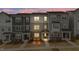 Modern townhomes with gray siding, stone accents, covered entries, and landscaped front yards offer curb appeal at dusk at 1430 Rosepine Dr, Cary, NC 27519