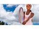 Smiling Personal in pink sportswear stands with a tennis racket against a bright blue sky at 162 Lookout Rdg # 677, Pittsboro, NC 27312