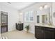 Bright bathroom featuring double sinks with dark wood cabinets, decorative shutters on the window, and neutral tile flooring at 1951 Mostyn Ln, Apex, NC 27502