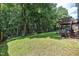 Lush trees and green grass in the backyard next to a deck and set of chairs at 2114 Frissell Ave, Apex, NC 27502