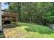 View of backyard with green grass, lush trees and partially covered furniture at 2114 Frissell Ave, Apex, NC 27502