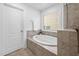 A bathroom featuring a modern soaking tub with stone surround and a window that provides natural light at 2117 Mckenzie Ridge Lane Ln, Apex, NC 27502