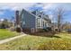 View of a blue sided townhome featuring a brick chimney, manicured lawn, and trimmed shrubs at 2820 Bedfordshire Ct, Raleigh, NC 27604