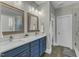 Stylish bathroom featuring double sinks, framed mirrors, navy cabinets, and a glass-enclosed shower at 3582 Cotton Field Ct, Wake Forest, NC 27587