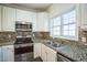 A kitchen features white cabinets, stainless steel appliances, and granite countertops at 4120 Standing Rock Way, Raleigh, NC 27604
