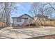 View of the home's exterior, featuring a deck, concrete driveway, and a well-maintained yard with a wooded backdrop at 723 Holloway St, Durham, NC 27701