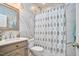 Bathroom with marble walls, new sink, and new toilet under a patterned curtain at 723 Holloway St, Durham, NC 27701