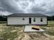 Home's backyard shows a concrete slab, siding, and newly installed roof at 73 Grace Pond Ave, Benson, NC 27504