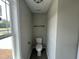Compact half bathroom with a toilet, towel bar, and small window providing natural light at 73 Grace Pond Ave, Benson, NC 27504
