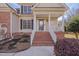 Close-up of an inviting front porch with brick steps, white railings, and tasteful landscaping at 100 Watkins Farm Rd, Rolesville, NC 27571
