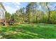 Expansive backyard featuring a lush green lawn, mature trees, and a wooden deck, offering a serene outdoor space at 1154 Smith Creek Way, Wake Forest, NC 27587