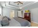 Well-lit bedroom featuring a tray ceiling, ceiling fan, and a classic wooden dresser with a television at 1154 Smith Creek Way, Wake Forest, NC 27587