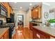Well-lit kitchen boasts hardwood floors, wood cabinetry, and stainless steel appliances at 1154 Smith Creek Way, Wake Forest, NC 27587