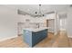 Bright kitchen with white cabinets, an island with sink, and modern lighting, adjacent to the living area at 140 Pilot Ridge Rd, Zebulon, NC 27597
