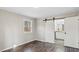 Bedroom featuring wood-look floors, board and batten walls and an ensuite bathroom with a sliding barn door at 2232 Miller Rd, Hillsborough, NC 27278
