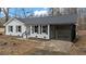 Charming white brick house with black shutters and a sunroom is seen on a bare front yard at 2232 Miller Rd, Hillsborough, NC 27278