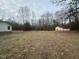 Wide grassy lot featuring a mobile home and a separate garage, surrounded by dense trees at 2232 Miller Rd, Hillsborough, NC 27278