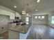 Open-concept kitchen featuring granite counters, an island, white cabinetry, and stainless appliances at 316 Olivia Crossing Ct # 11, Four Oaks, NC 27524