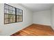 Bright bedroom featuring hardwood floors and a large black grid window with wooded views at 3622 Colchester St # 13, Durham, NC 27707