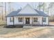 Exterior of a home featuring a charming front porch with seating, dark shutters, and a welcoming entrance at 5171 S River Rd, Lillington, NC 27546