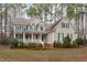 Charming two-story home boasts a welcoming front porch, complemented by lush landscaping and classic green shutters at 5309 Shoreline Ct, Holly Springs, NC 27540