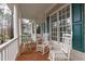 Charming front porch with rocking chairs, a porch swing, and a brick floor at 5309 Shoreline Ct, Holly Springs, NC 27540