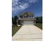 Two-story home featuring a spacious garage, gray siding, and a well-manicured front lawn on a sunny day at 542 Winding Crk Dr, Lillington, NC 27546