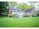 A backyard of a brick house with decks, awnings and lush green grass at 826 Warwick Ct, Burlington, NC 27215