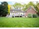 A backyard of a brick house with decks, awnings and lush green grass at 826 Warwick Ct, Burlington, NC 27215