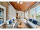 Inviting sunroom featuring brick walls, wood ceiling, white shelving, and wicker sofas with blue cushions at 826 Warwick Ct, Burlington, NC 27215